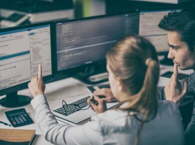 Una donna e un uomo sembrano essere attenti a software gestionale su misura su due monitor e comparano con attenzioni i dati del gestionale.